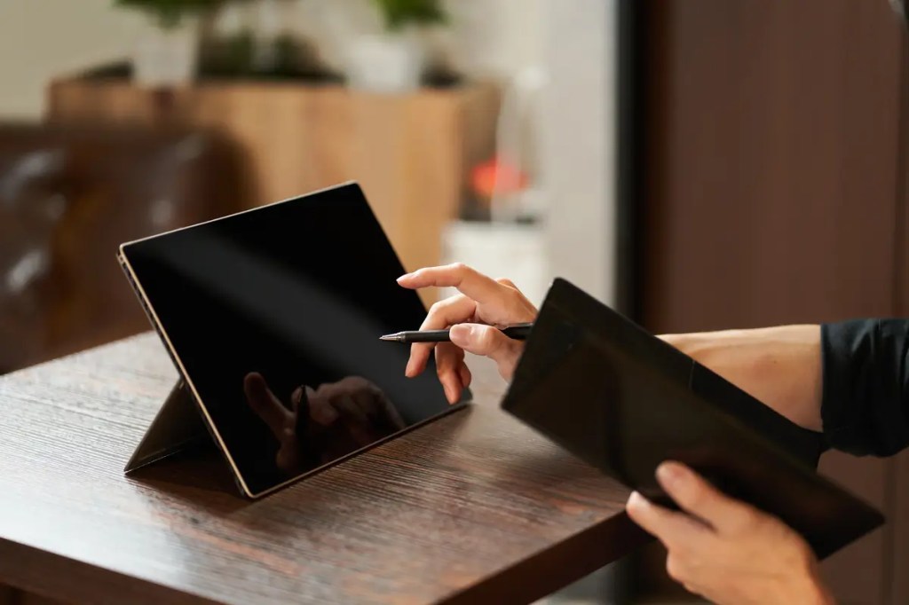 A person comparing laptop prices and specifications on a tablet, illustrating the research process for buying a new laptop at a senQ outlet in Malaysia.