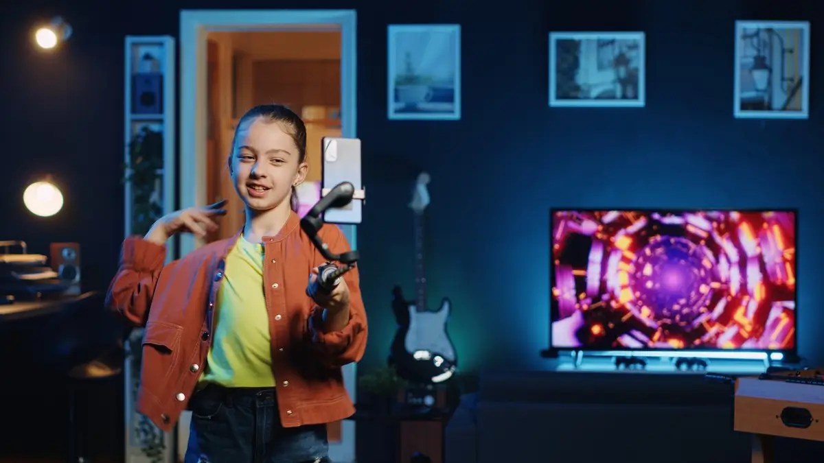 Girl filming a video in front of a glowing QLED TV. Discover why an AI TV is the perfect smart home companion.