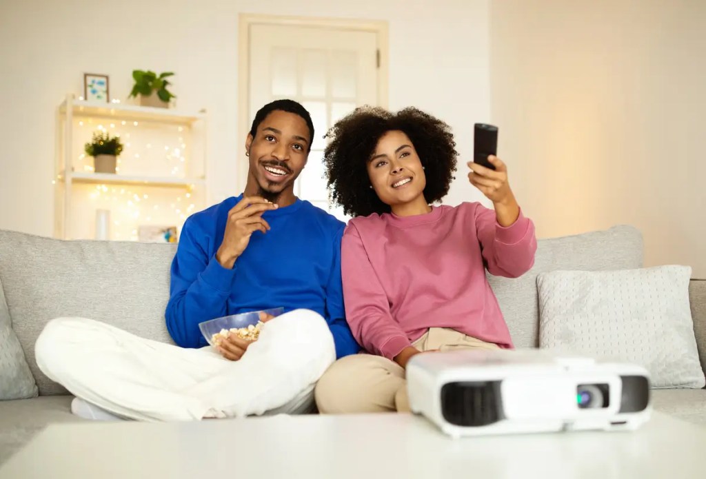 Couple on a couch using a portable Android smart projector. Connect it with your OPPO Find X Series smartphone.