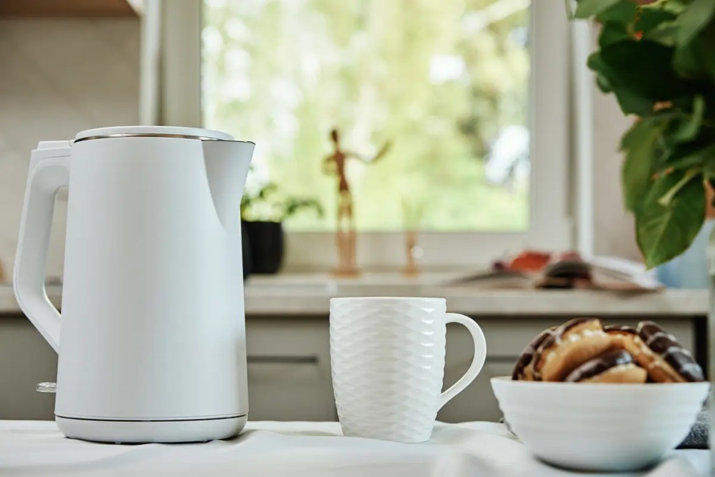 Buy electric kettle online guide from senQ Malaysia. A modern white kettle, a mug, and pastries on a kitchen counter.